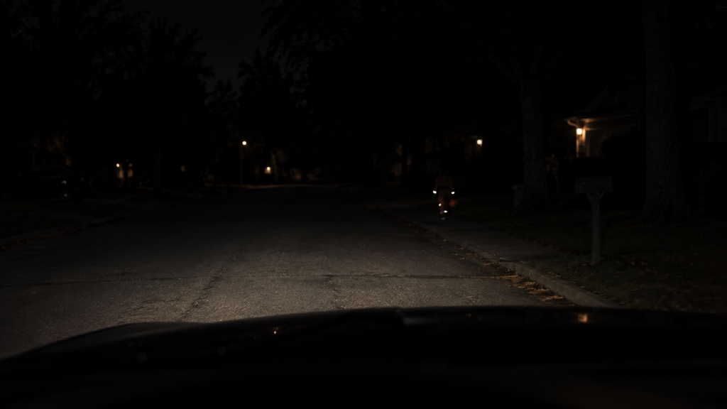 Driver's view showing retroreflective tape glowing brightly while fluorescent costume fabric appears dark under headlights.